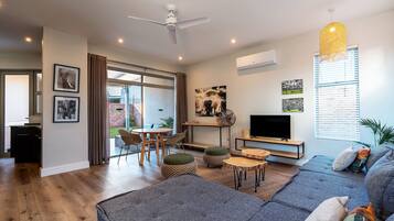 Una sala de estar moderna con un sofá, otomanas, una mesa de centro y un televisor.