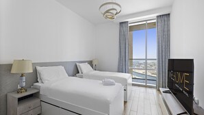 Una camera d'albergo moderna con due letti, una televisione, un comodino, una lampada e un'ampia finestra con vista.