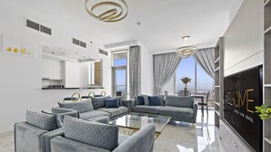 Un soggiorno moderno con un tavolino in vetro, divani grigi e un grande schermo TV che mostra la scritta "WELCOME".