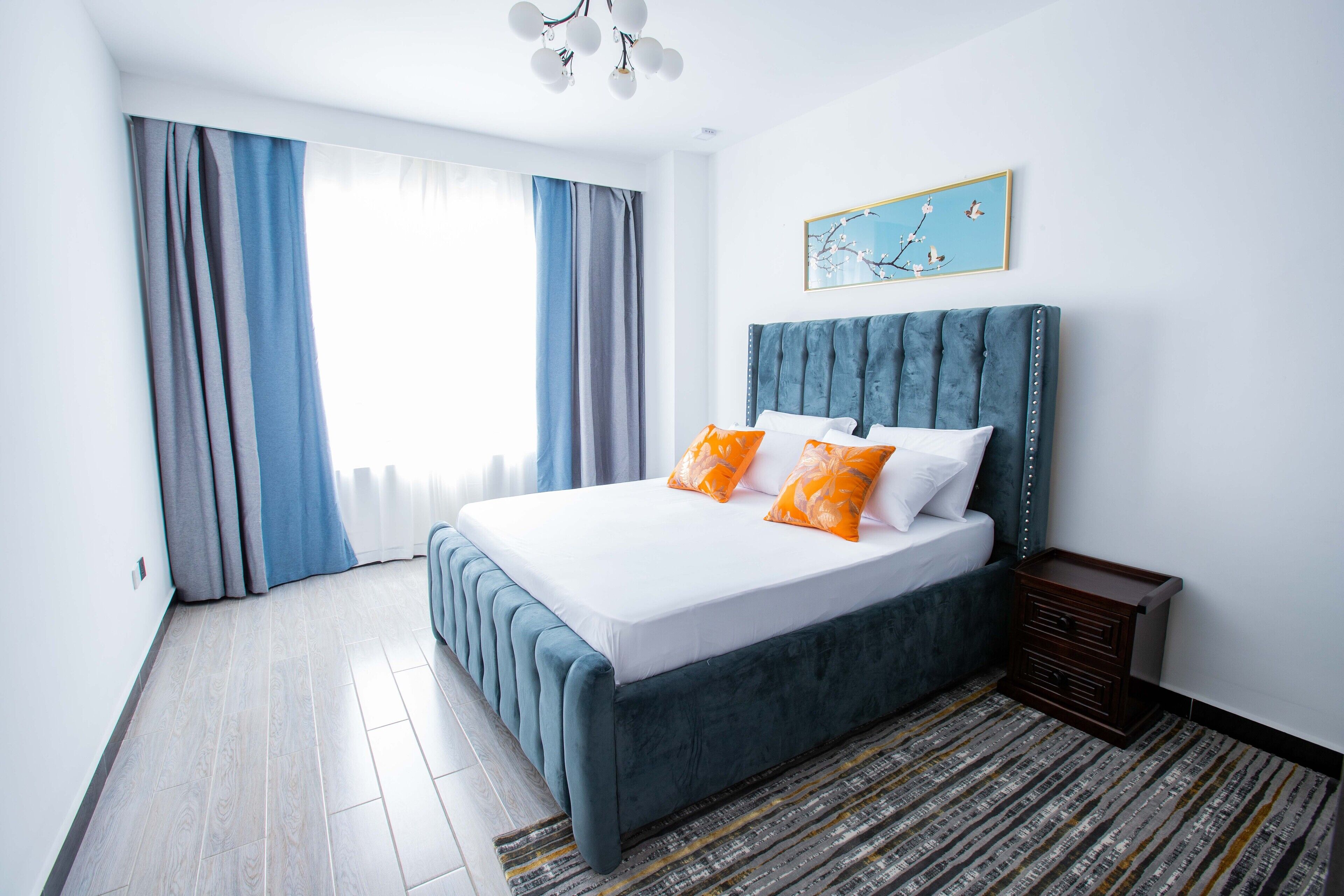 Ein modernes Schlafzimmer mit einem großen Bett, Blick ins Freie und einem Gemälde an der Wand.