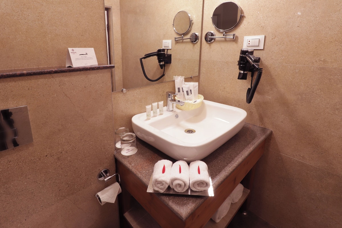 A bathroom with a sink, towel dispenser, and two mirrors.