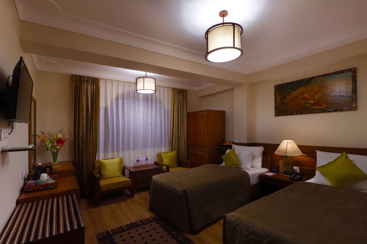 A hotel room with two beds, a television, a desk with a lamp, and a painting on the wall.
