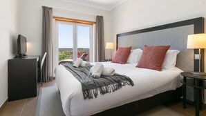 A hotel room with a large bed, a desk with a computer, a chair, a window with curtains, and a view of the outdoors. - Casa Serenidade - Vale de Ribeira (Arão (Mexilhoeira Grande))