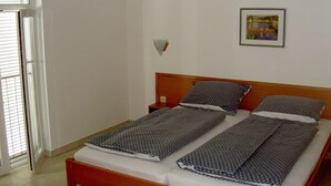 Ein Einzelbett mit Holz Kopfteil, weißer Bettwäsche und gemusterten Kissen.