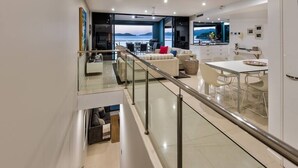 A modern interior with a glass railing, a dining area, and a view of the sea. - Edge Apartment 15, Edge Apartment 15 on Hamilton Island (Hamilton Island)