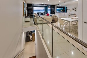 A modern interior with a glass railing, a dining area, and a view of the sea. - Edge Apartment 15, Edge Apartment 15 on Hamilton Island (Hamilton Island)