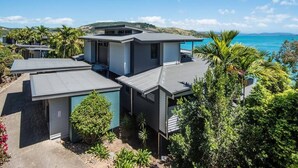 A modern house with a flat roof, surrounded by lush greenery and a view of the ocean. - Edge Apartment 15, Edge Apartment 15 on Hamilton Island (Hamilton Island)