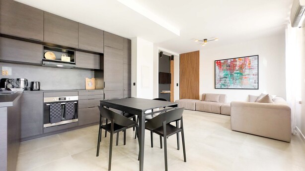A modern kitchen with a dining area, a sofa, and a large abstract painting. - Le Riviera (Cannes)