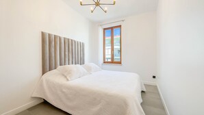 A bedroom with a bed, a window, and a ceiling light fixture. - Le Riviera (Cannes)