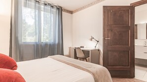 Een slaapkamer met een bed, een bureau en een deur.