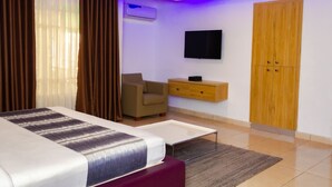 Una habitación de hotel moderna con una cama, un televisor, un armario de madera y un escritorio con una silla.
