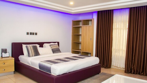 Un dormitorio moderno con una cama grande, un armario de madera y una mesita de noche con una lámpara.