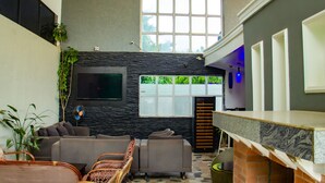 Un interior moderno con una pared de piedra, un ventanal grande y una zona de estar con sofás y sillones.
