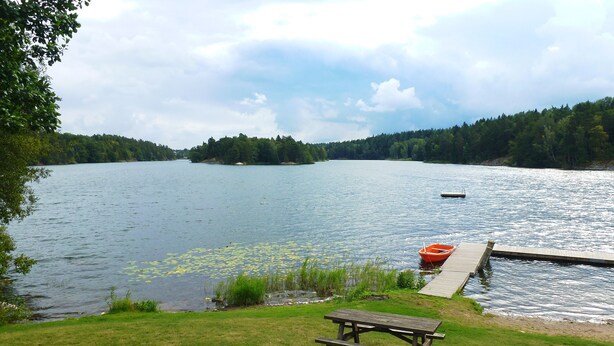 A lakeside picnic area with a dock and a boat. - Experience the Ultimate in Comfort and Serenity (Stockholms län)