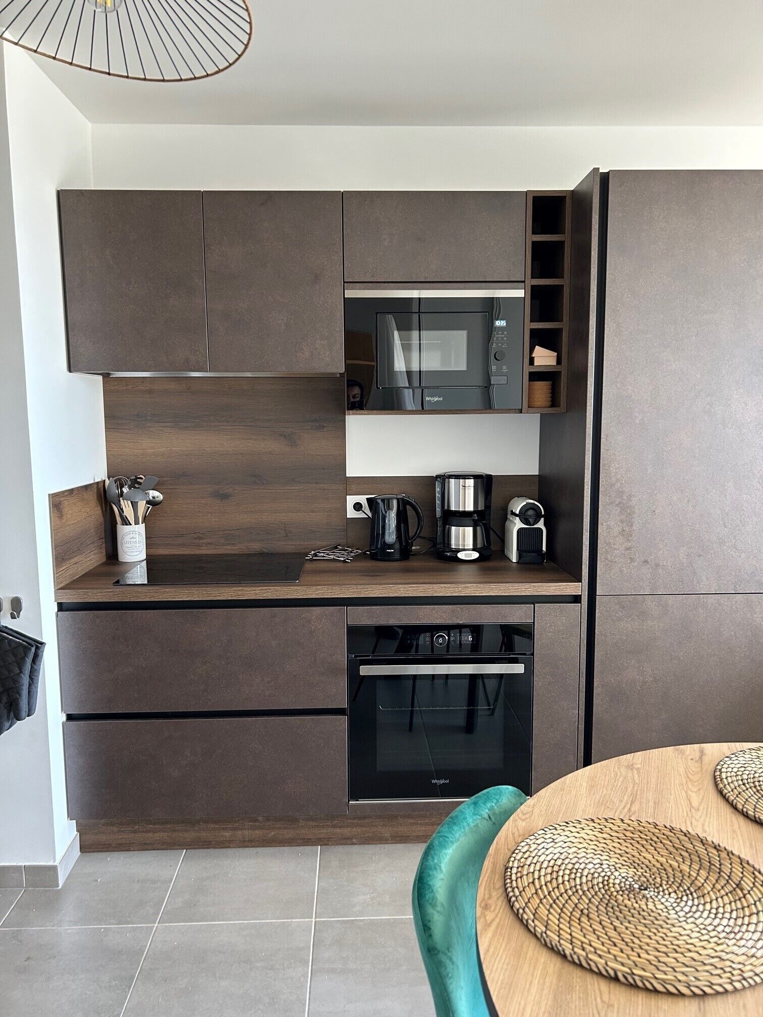 A modern kitchen with dark cabinetry, a built-in microwave, a coffee maker, and a dishwasher.