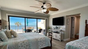 A bedroom with a large bed, a desk, and a TV. - NEW! Luxuriously Updated & Renovated Beachfront Retreat- Walkable to Fun!! (Madeira Beach)