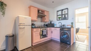 A compact kitchen with a refrigerator, oven, microwave, and washing machine. - Afton (Lancaster)