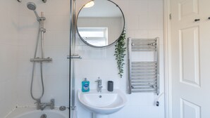 A bathroom with a bathtub, a sink, a mirror, and a shower. - Afton (Lancaster)