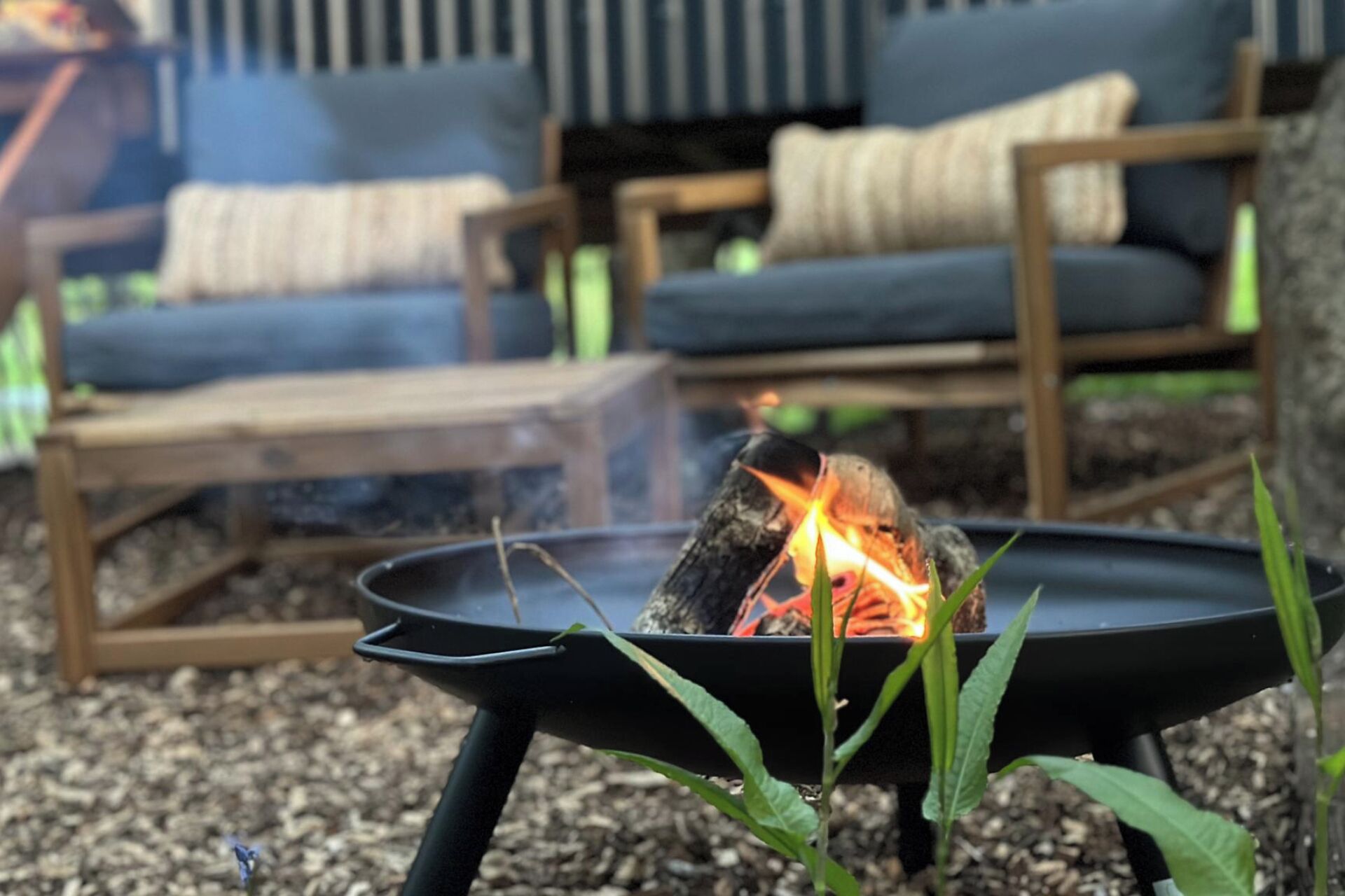 A fire pit with a burning log surrounded by outdoor furniture.