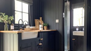 Une cuisine avec des meubles de rangement en bois foncé, un plan de travail en bois, un évier, une fenêtre et une plante.
