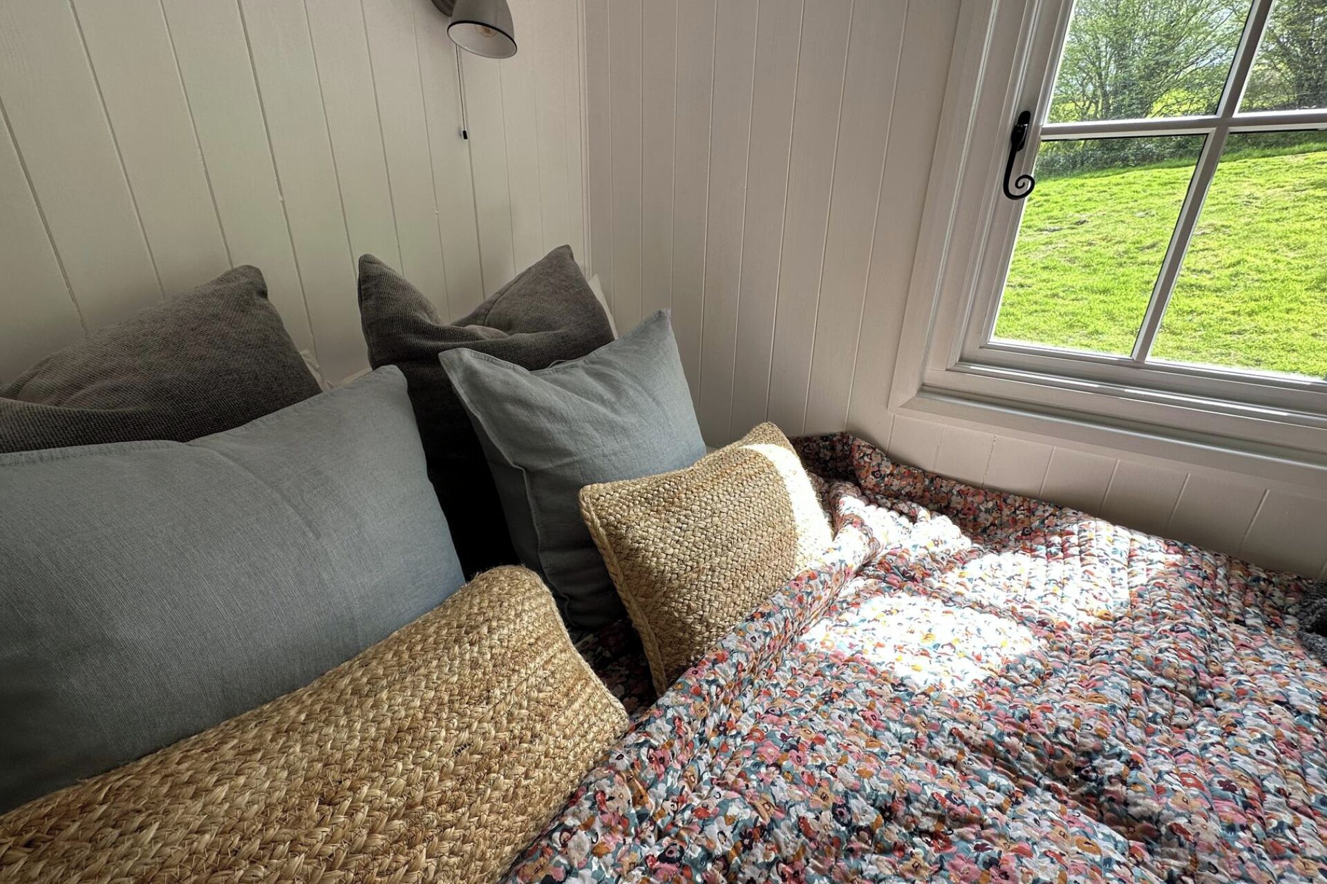Una habitación acogedora con cama, almohadas y ventana con vistas a un espacio verde.