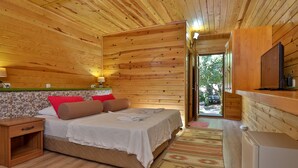 A wooden cabin bedroom with a bed, bedside table, and a small desk with a chair. - Çıralı Orange Motel (Kemer)