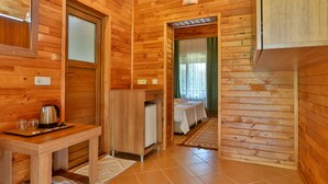 A wooden cabin interior with a kitchenette, a bed, and a bathroom. - Çıralı Orange Motel (Kemer)
