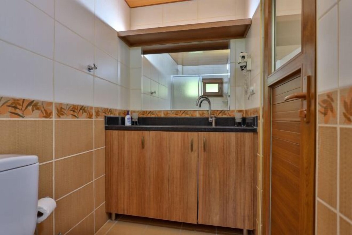 A bathroom with a wooden vanity, a mirror, and a toilet.