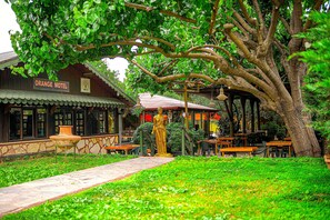 A building labeled 'Orange Motel' with outdoor seating and a statue. - Çıralı Orange Motel (Kemer)