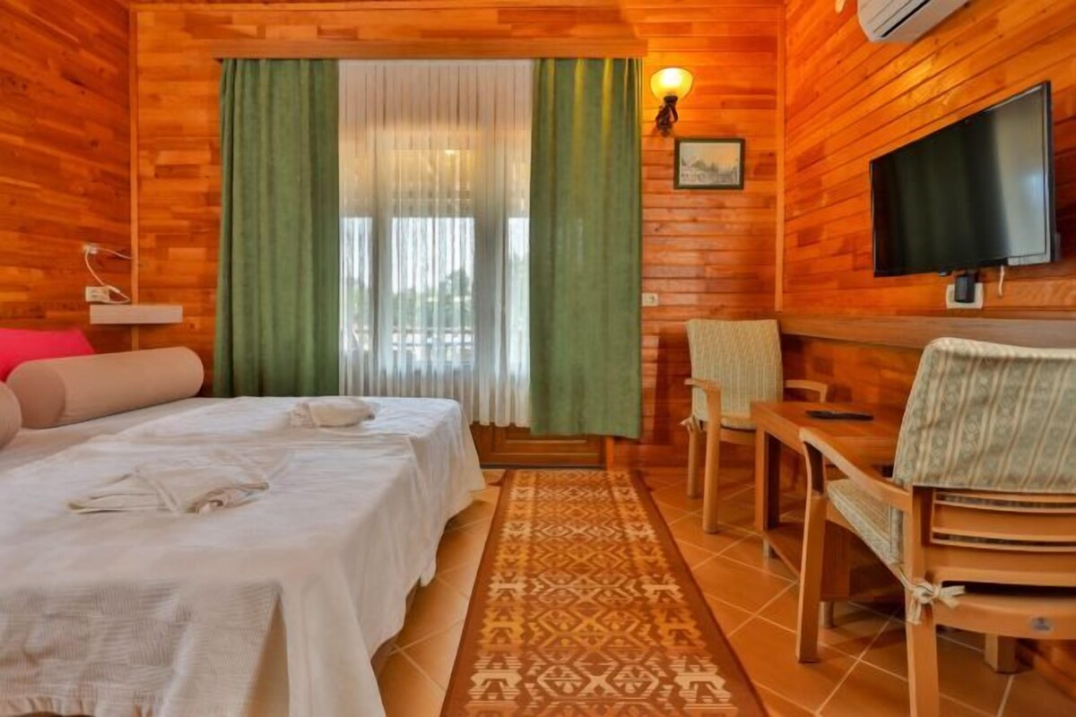 A wooden cabin room with two beds, a TV, and a small table.