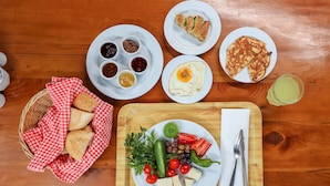 A wooden table with various food items including bread, eggs, and vegetables. - Çıralı Orange Motel (Kemer)