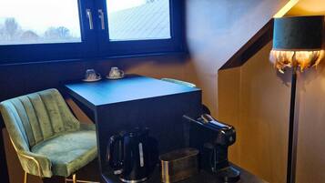 Una habitación compacta con escritorio, silla, cafetera y lámpara.
