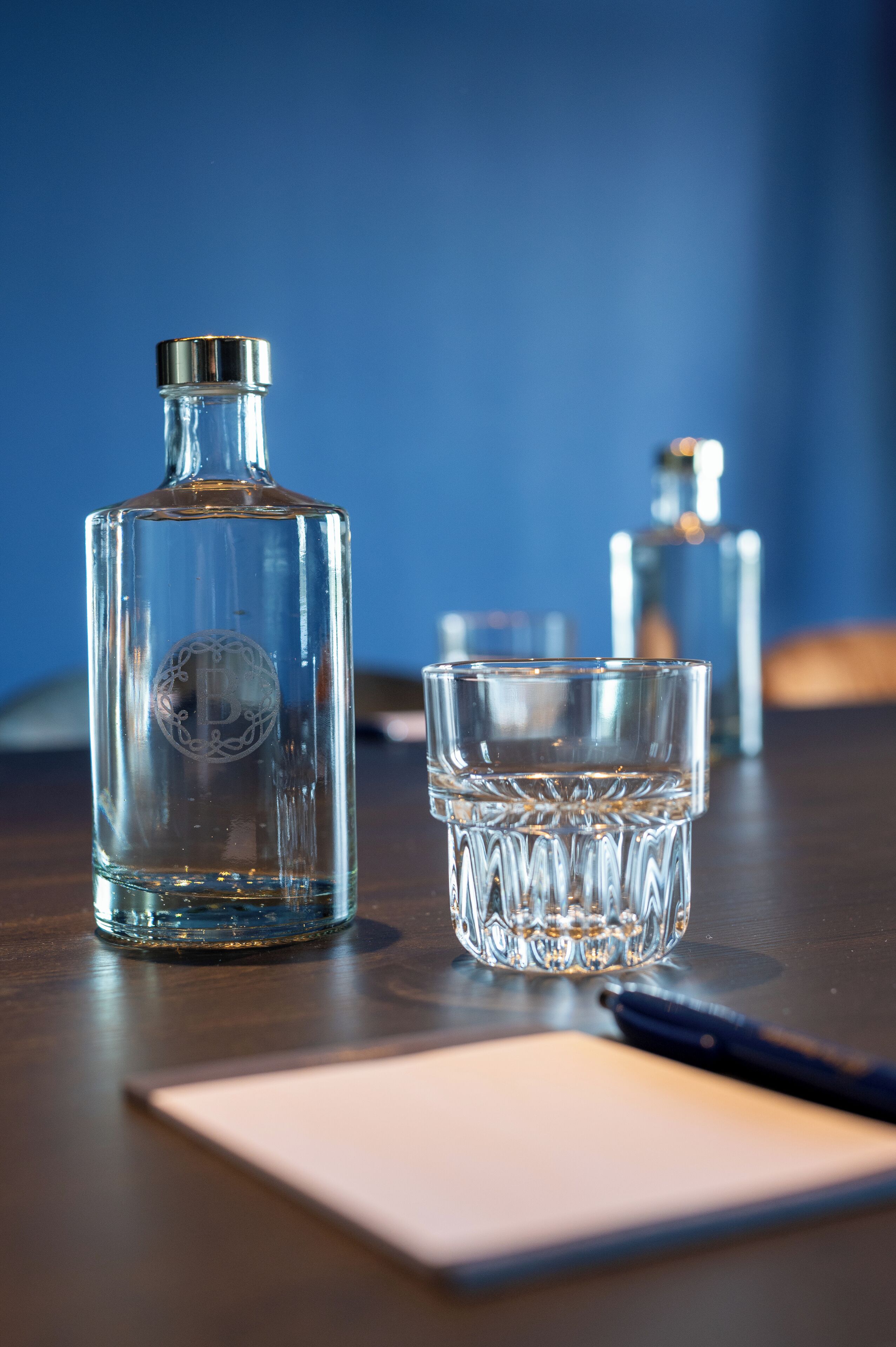 A clear glass bottle and a glass on a wooden table.