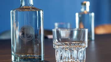 A clear glass bottle and a glass on a wooden table.