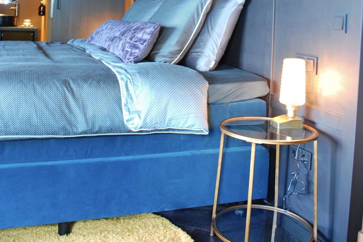 A bedroom with a bed, a round side table, and a mirror.