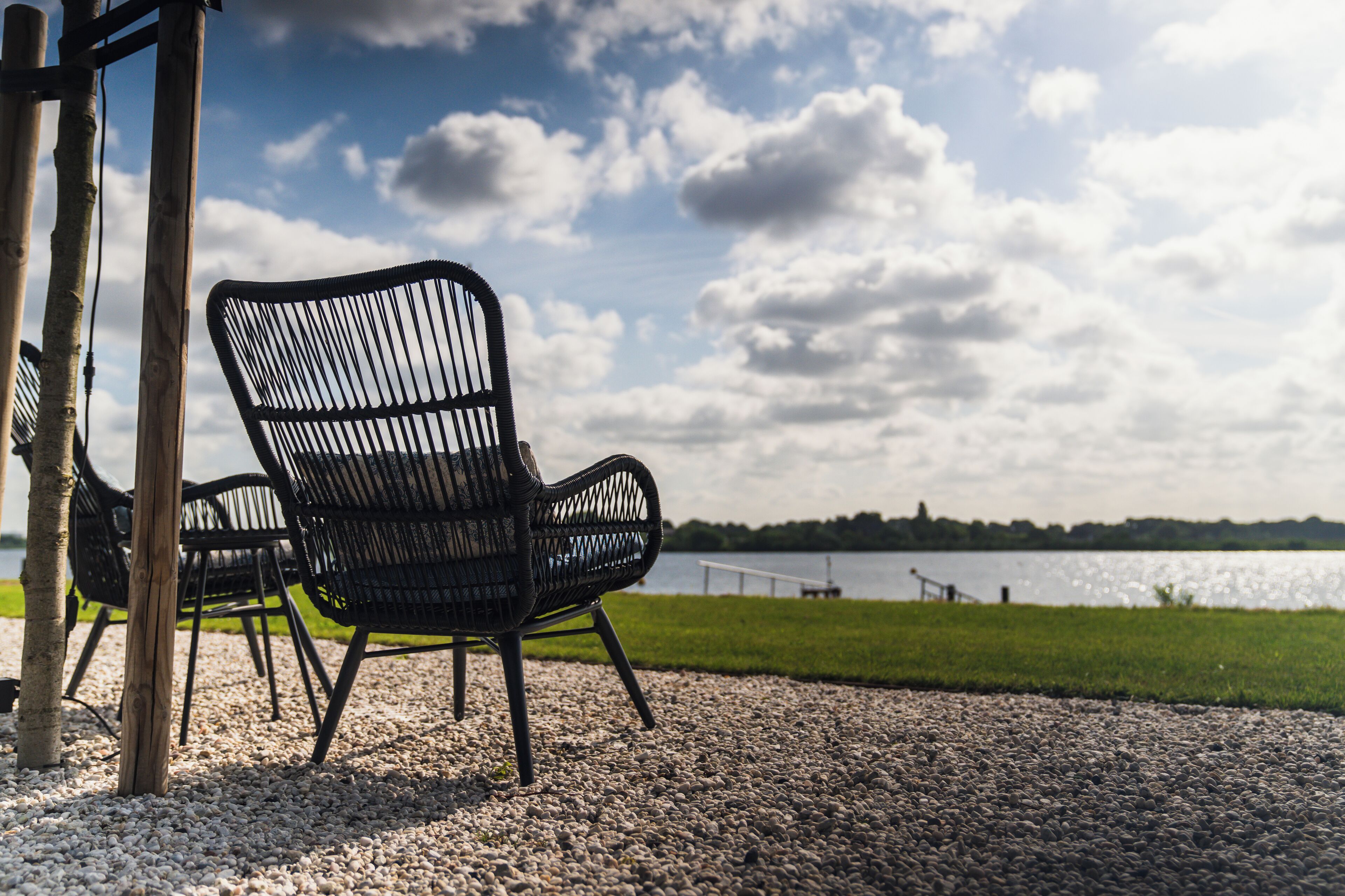 Een grindpad met twee zwarte stoelen en een houten constructie.