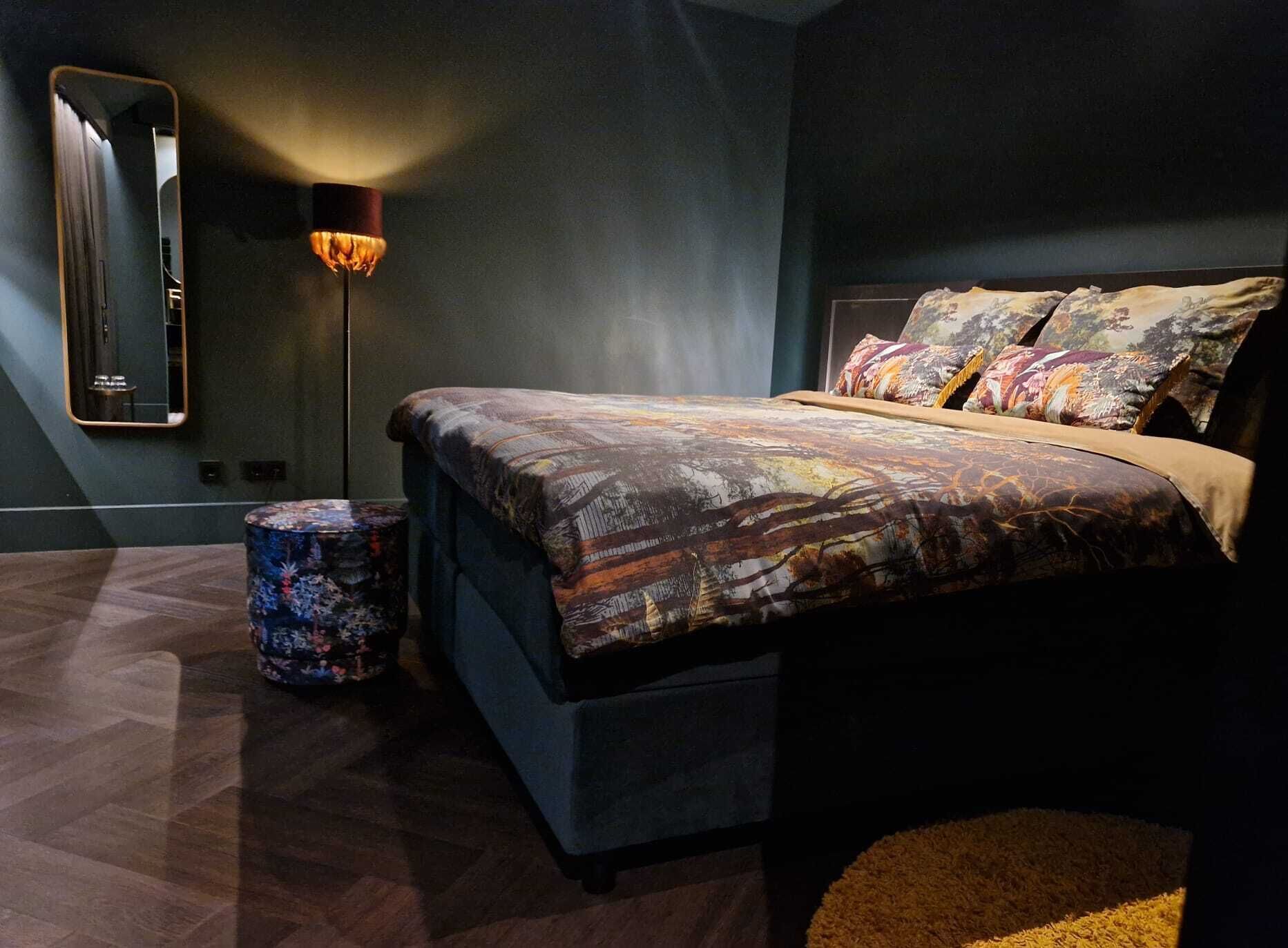 A modern bedroom with a large bed, a floor lamp, and a round side table.