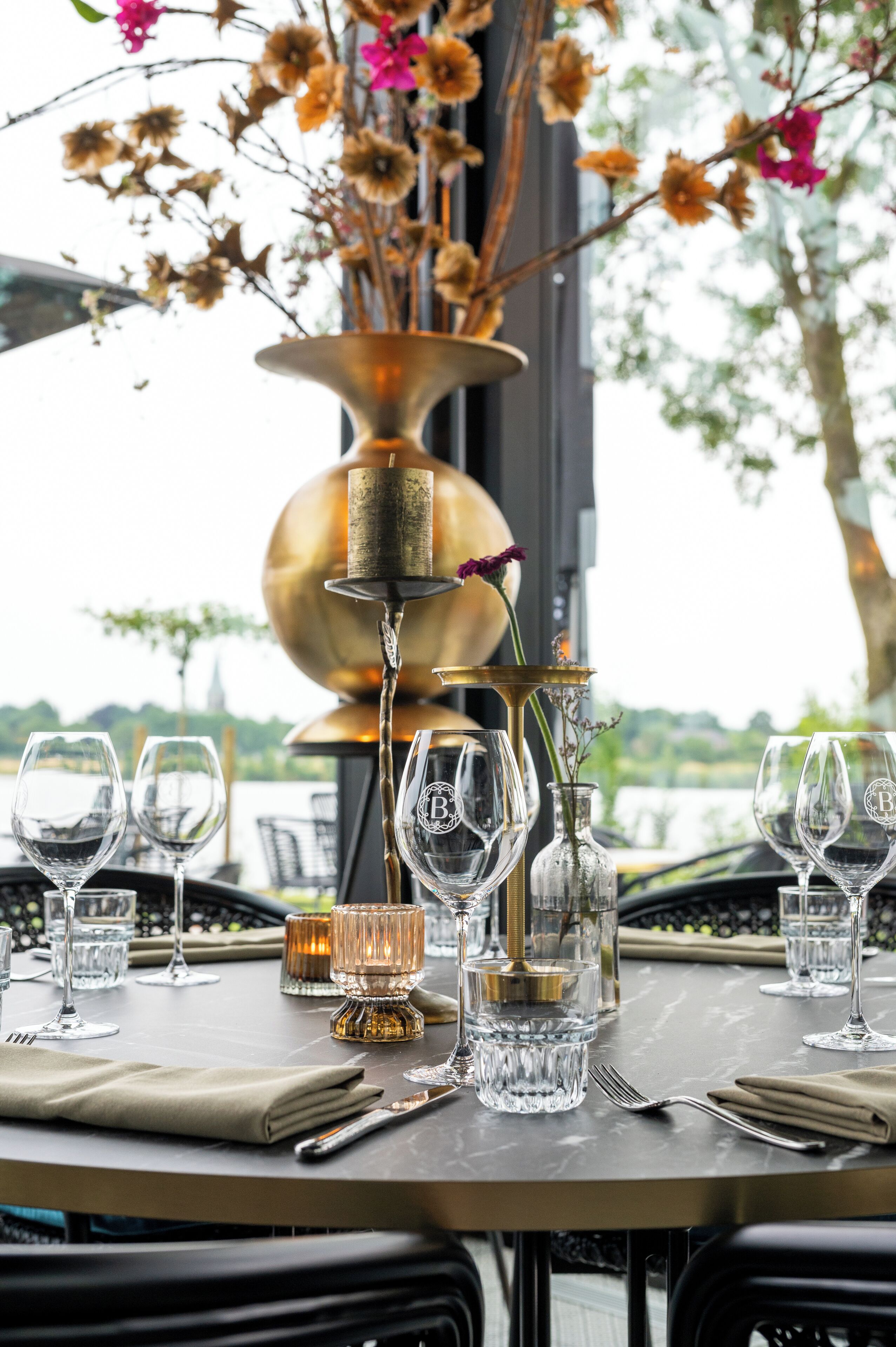 A table set for dining with wine glasses, a candle, and a vase with flowers.