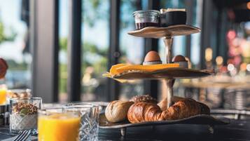 A breakfast setup with croissants, orange juice, and a tiered serving tray with eggs and coffee.