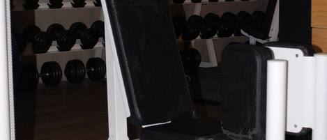 A gym with a TECA bench press, weight racks, and a mirror on the wall.