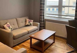 Relax in this cozy space with a sofa, coffee table, and chair, offering a view of the urban landscape.