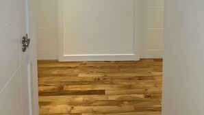 A hallway with wooden flooring, white walls, and a framed artwork on the wall. - Inverness Highland Apartment (Inverness)