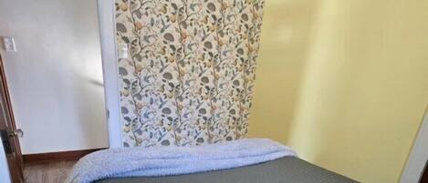 A room with a bed, a door, and a patterned wallpaper.
