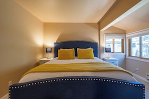Une chambre à coucher avec un lit, des tables de chevet, une lampe et une fenêtre.
