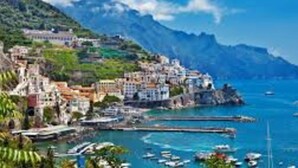 A coastal town with buildings along the waterfront, boats docked, and a mountainous backdrop. - Seafront Apartment for Rent 6 Sleeps Skyscraper (Fermo)