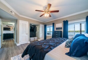 A bedroom with a bed, a ceiling fan, a window with curtains, and a view of the outdoors.