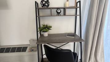 A compact workspace with a desk, chair, and a wall-mounted shelf with decorative items.