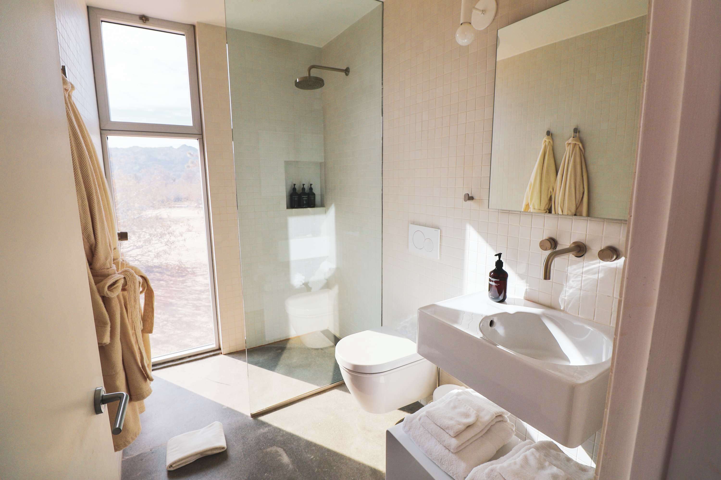 Un baño moderno con cabina de ducha de vidrio, lavamanos blanco y espejo grande.
