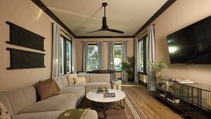 A modern living room with a sectional sofa, a round coffee table, and a TV mounted on the wall. - Chic, Marigny Retreat | Heated Pool (New Orleans)
