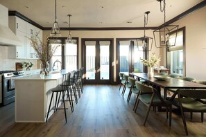 Cozinha moderna com ilha central, banquetas e iluminação pendente.